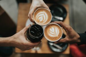 A group of friends holding different beverages, including coffee, viewed from above.