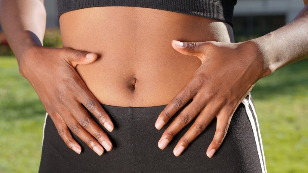 Woman holding her stomach, focusing on gut health and weight loss.