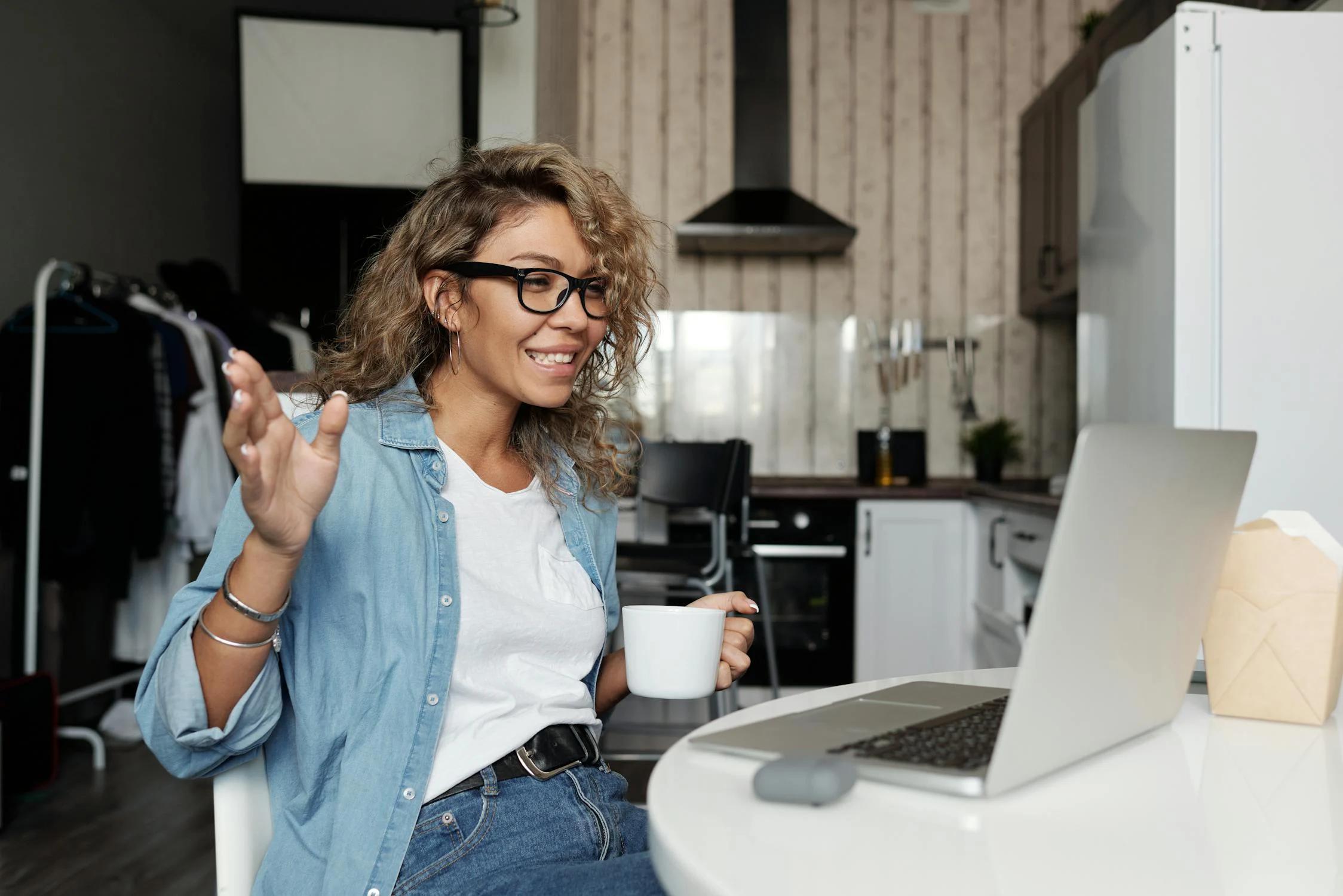 A woman drinking coffee while working on her laptop at home, starting her day with focus and energy.