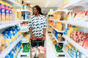 A woman in a supermarket aisle scanning food products.