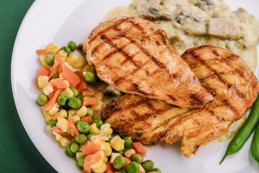A plate with grilled chicken and vegetables.