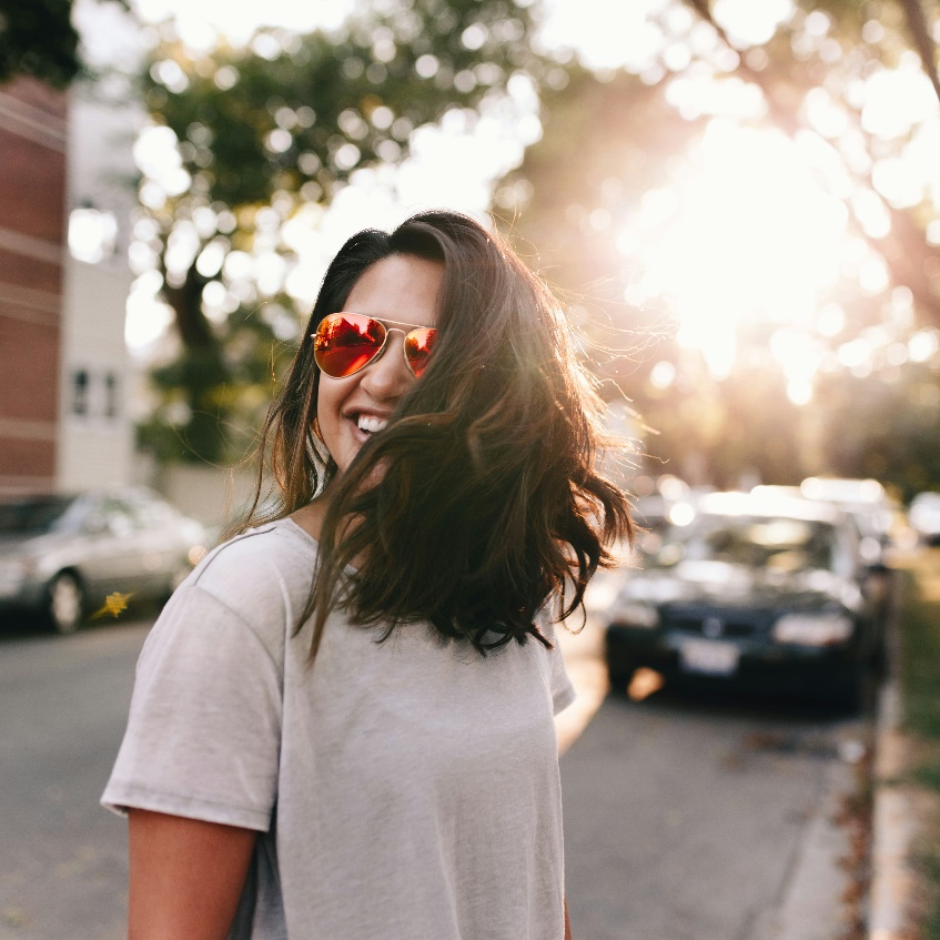 A smiling woman outdoors on a sunny day.