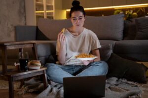 A picture of a person eating junk while watching a movie