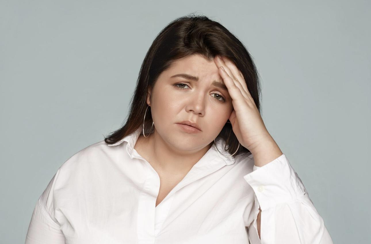A woman holding her head, looking visibly stressed or overwhelmed.