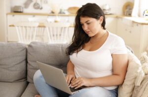A woman researching sustainable weight loss methods without injections on a laptop.